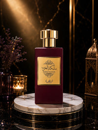 Flacon de parfum My Store Malikat Al Arab bordeaux avec étiquette dorée sur un socle en marbre dans une ambiance luxe