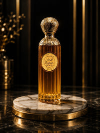 Flacon de parfum My Store Qasas Gold en verre ambré avec capuchon doré ciselé sur un socle en marbre luxueux